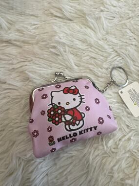 Hello Kitty pink coin purse holding a bouquet of flowers and small pink flowers